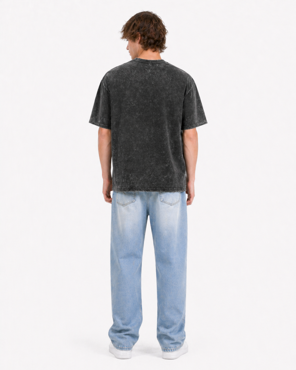Man in black acid wash t-shirt and blue jeans viewed from the back on white background