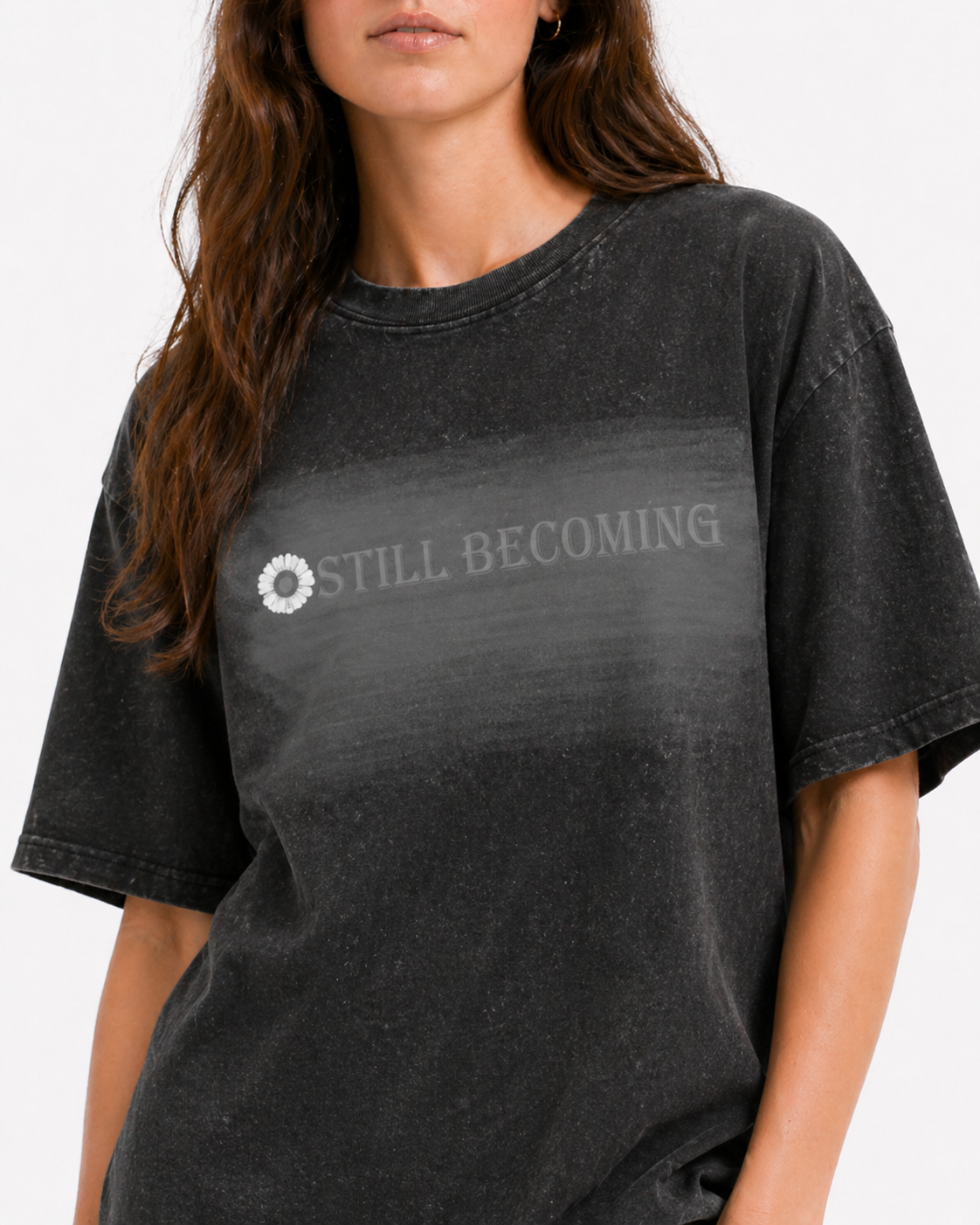 Model in oversized dark grey acid-wash t-shirt with sunflower logo and STILL BECOMING text